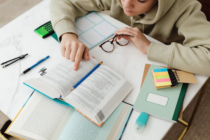 Student studying with a textbook, notes, and calculator for Grade 12 Maths revision